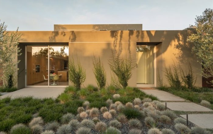 Plastered residence entry at dusk behind a planted garden